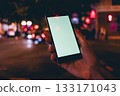 Person is holding a cell phone in a dark city street 133171043