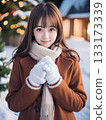Young woman smiling on a snowy night with sparkling Christmas lights 133173339