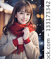Young woman smiling on a snowy night with sparkling Christmas lights 133173342