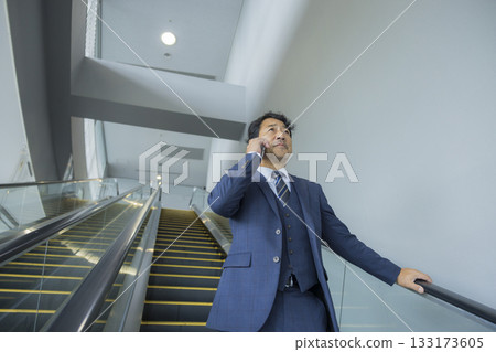 Businessman riding escalator Businessman riding escalator 133173605