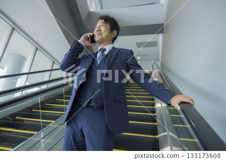 Businessman riding escalator Businessman riding escalator 133173608