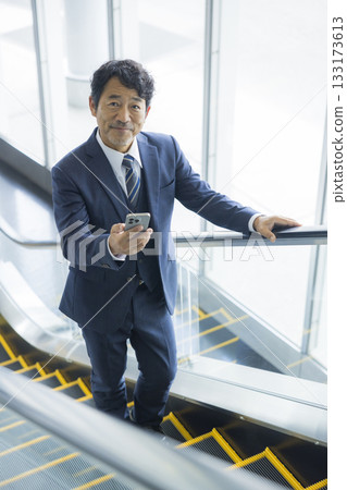 Businessman riding escalator 133173613