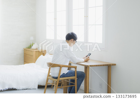 男人在臥室看智慧型手機 133173695