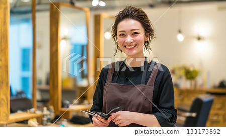 一位熱情友善、笑容可掬的女美髮師正在工作，她竭盡全力讓顧客展現出最佳狀態。 133173892