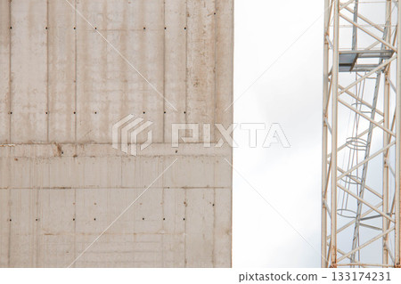 Concrete Wall Frame of Building under Construction with Formwork Prints. Architectural origin of Structure. Monolithic Surface with Tower Crane Nearby at Construction Site. Concrete Wall Frame of Building under Construction with Formwork Prints. Architectural origin of Structure. Monolithic Surface with Tower Crane Nearby at Construction Site. 133174231