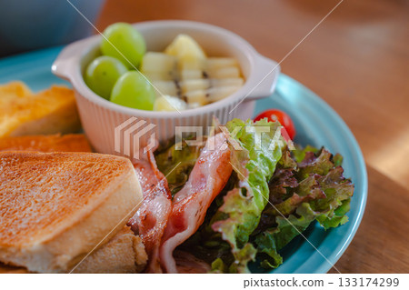 A colorful breakfast plate featuring toast, fried eggs, bacon and fruit A colorful breakfast plate featuring toast, fried eggs, bacon and fruit 133174299