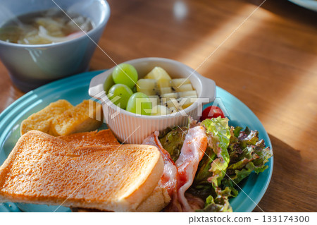 A colorful breakfast plate featuring toast, fried eggs, bacon and fruit A colorful breakfast plate featuring toast, fried eggs, bacon and fruit 133174300