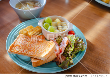 一份色彩繽紛的早餐拼盤，包括吐司、煎蛋、培根和水果。 133174303