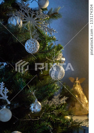 Festive Christmas tree decorated with red and golden ornaments, glowing string lights, creating a warm holiday atmosphere. 133174304