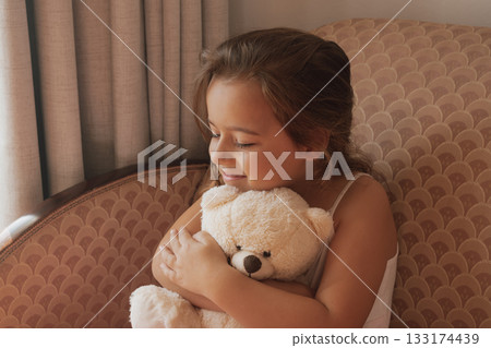 Genuine happiness: a smiling girl embraces her teddy bear with overwhelming affection Genuine happiness: a smiling girl embraces her teddy bear with overwhelming affection 133174439