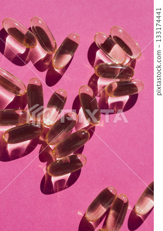 Pop art vitality: bright yellow nutritional capsules scattered across a vivid pink canvas Pop art vitality: bright yellow nutritional capsules scattered across a vivid pink canvas 133174441