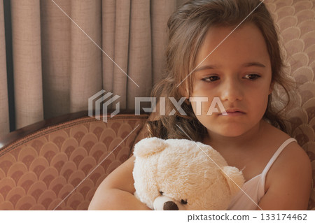 Inner world: girl holding a bear, reflecting a private moment of quiet childhood turmoil 133174462