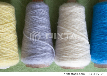 Variety colours of alpaca wool and silk. Cones of multicoloured yarn. Wool threads in a row. Row of blue, white, yellow and grey wool. Knitting hobby. Bobbins of yarn. Bright wool for knitting.  133175173