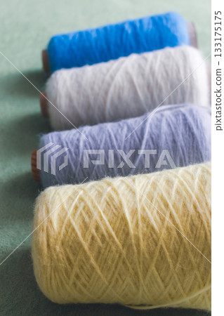 Variety colours of alpaca wool and silk. Cones of multicoloured yarn. Wool threads in a row. Row of blue, white, yellow and grey wool. Knitting hobby. Bobbins of yarn. Bright wool for knitting. Variety colours of alpaca wool and silk. Cones of multicoloured yarn. Wool threads in a row. Row of blue, white, yellow and grey wool. Knitting hobby. Bobbins of yarn. Bright wool for knitting. 133175175