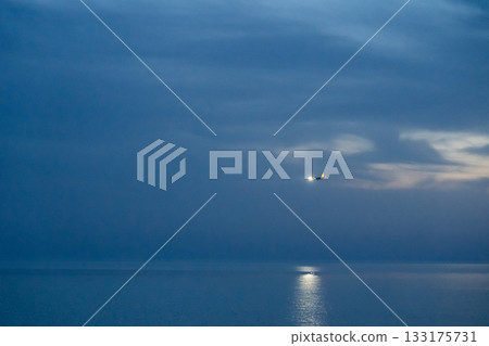 A plane coming in for landing at night, flying over the sea 133175731