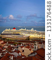 Two large cruise ship manoeuvre by terminal pier near historic center of Lisbon, Portugal. Alfama area, original buildings with red-tiled rooftops, cloudy sky at afternoon. Travel destination, voyage 133176488