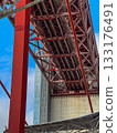 Upshot view of tower beam, main girder and anchorage block of famous red April 25th or 25 de Abril bridge in Lisbon, Portugal, blue sky, white clouds on sunny day. Tourist attraction, travel 133176491