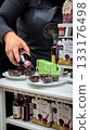 Obidos, Portugal - Dec 30, 2023: Female hand pouring traditional Portuguese ginja liqueur into edible chocolate cups, sweet cherry drink, popular local specialty and tourist souvenir. Authentic 133176498