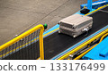 Single grey suitcase travels on conveyor belt loader, ready to be loaded into cargo hold of airplane. Essential ground handling logistics on tarmac before departure, start of journey and travel 133176499
