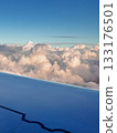 Beautiful view shot from airplane window flying above fluffy clouds in blue sky on sunny day, airplane wing from window seat, sky panorama, adventure, wanderlust, freedom, tranquility. Ideal for 133176501