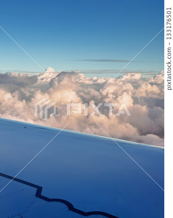 Beautiful view shot from airplane window flying above fluffy clouds in blue sky on sunny day, airplane wing from window seat, sky panorama, adventure, wanderlust, freedom, tranquility. Ideal for Beautiful view shot from airplane window flying above fluffy clouds in blue sky on sunny day, airplane wing from window seat, sky panorama, adventure, wanderlust, freedom, tranquility. Ideal for 133176501