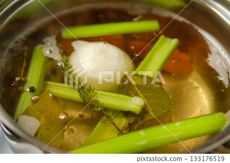 Cooking flavorful vegetable broth with fresh herbs and vegetables in a pot 133176519