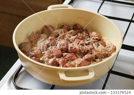 Cooking beef in a large pot on a stove with bubbling juices and tender pieces Cooking beef in a large pot on a stove with bubbling juices and tender pieces 133176524