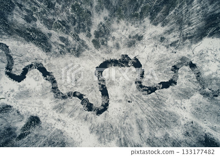Aerial view of the winding river against the backdrop of snowy fields and winter forest. Meander from the top 133177482