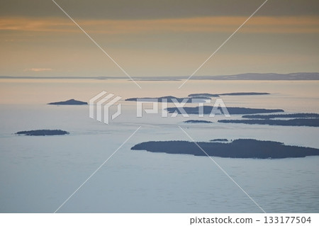 Landscape: islands among snowy fields in the frozen white sea in winter. Landscape: islands among snowy fields in the frozen white sea in winter. 133177504