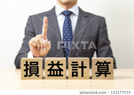 一塊寫著「利潤與虧損」字樣的磚塊和一個商人 一塊寫著「利潤與虧損」字樣的磚塊和一個商人 133177535