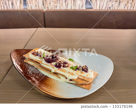 Gourmet mille feuille pastry with vanilla cream and berry compote served on ceramic plate restaurant 133178196