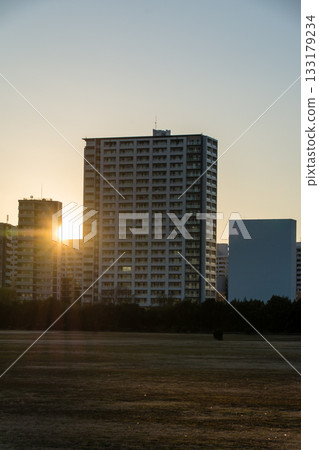 The setting sun shining through the buildings of Kawasaki across the Tama River and the riverbank of the Tama River The setting sun shining through the buildings of Kawasaki across the Tama River and the riverbank of the Tama River 133179234