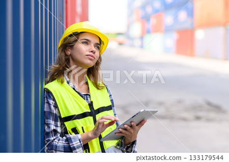 Engineer women wear yellow helmets and reflection shirts working on tablet computers to check inventory details of containers box. Inspector or Safety Supervisor in Container Terminal. Engineer women wear yellow helmets and reflection shirts working on tablet computers to check inventory details of containers box. Inspector or Safety Supervisor in Container Terminal. 133179544