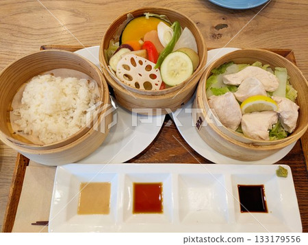 A healthy Japanese meal of chicken and colorful steamed vegetables served in a bamboo steamer 133179556