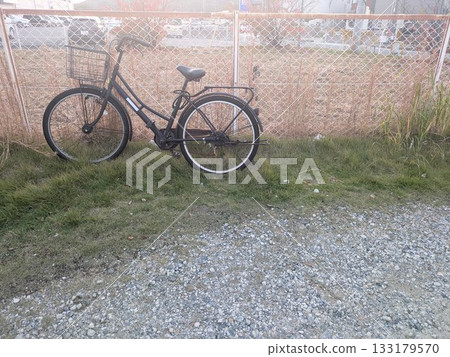 一輛鏽跡斑斑的自行車被遺棄在鐵絲網和雜草之間。 一輛鏽跡斑斑的自行車被遺棄在鐵絲網和雜草之間。 133179570