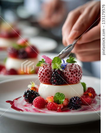Delicate hands artfully plating a gourmet dessert with fresh berries 133179576