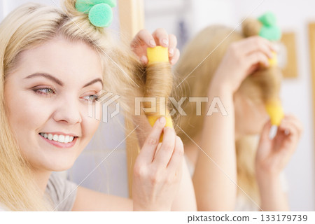 Blonde woman using hair rollers 133179739