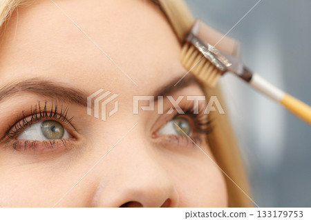 Woman brushing her eyebrows Woman brushing her eyebrows 133179753
