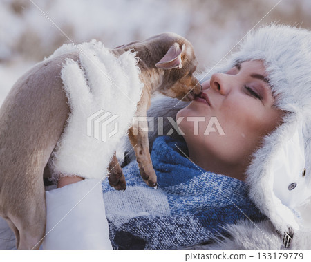 Woman playing with dog during winter 133179779