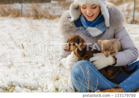 Woman playing with dogs during winter 133179780