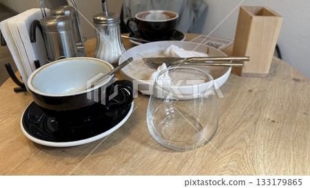 Coffee shop table with empty cups and crockery showcasing post-meal setting with utensils 133179865