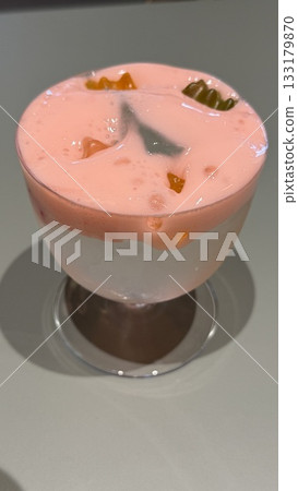 Glass of pink fruit jelly dessert with gummy candies in light background 133179870