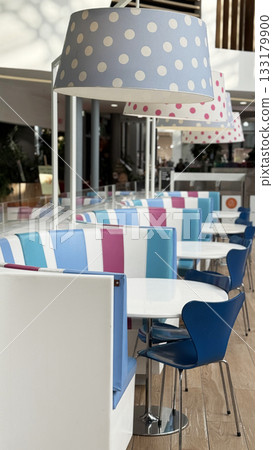 Empty modern cafe interior with colorful seating and polka dot lampshades in natural light Empty modern cafe interior with colorful seating and polka dot lampshades in natural light 133179900