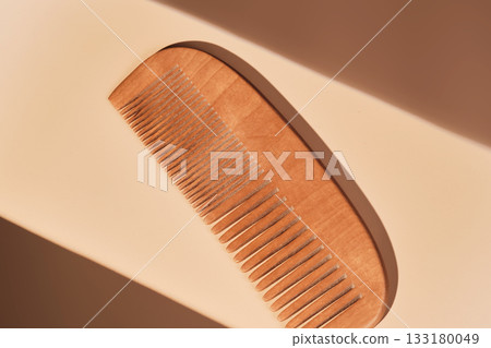 Wooden comb on beige background receiving sunlight Wooden comb on beige background receiving sunlight 133180049