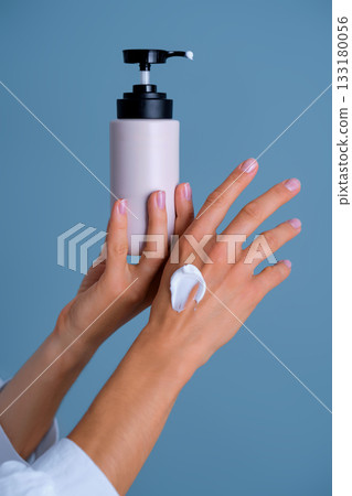 Woman applying moisturizing cream from pump bottle Woman applying moisturizing cream from pump bottle 133180056