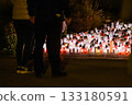 Woman Standing Before Hundreds of Glowing Memorial Candles During a Nighttime Remembrance 133180591