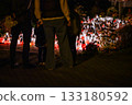 Woman Standing Before Hundreds of Glowing Memorial Candles During a Nighttime Remembrance 133180592