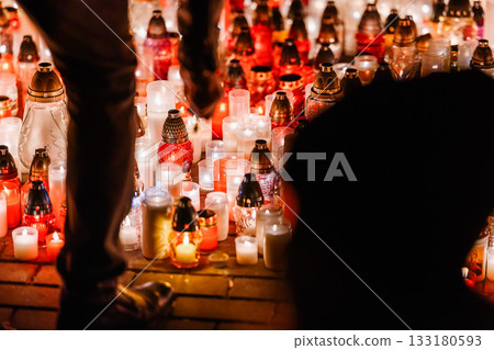 Woman Standing Before Hundreds of Glowing Memorial Candles During a Nighttime Remembrance 133180593