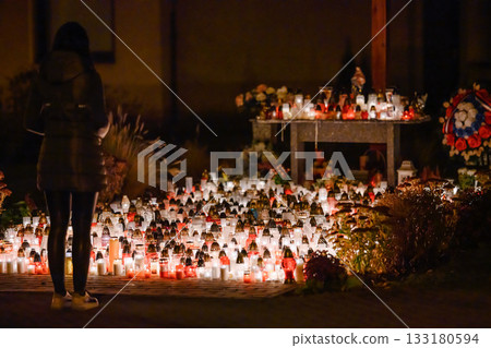 Woman Standing Before Hundreds of Glowing Memorial Candles During a Nighttime Remembrance 133180594