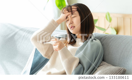 一位身體不適的女士正在測量體溫 一位身體不適的女士正在測量體溫 133180611